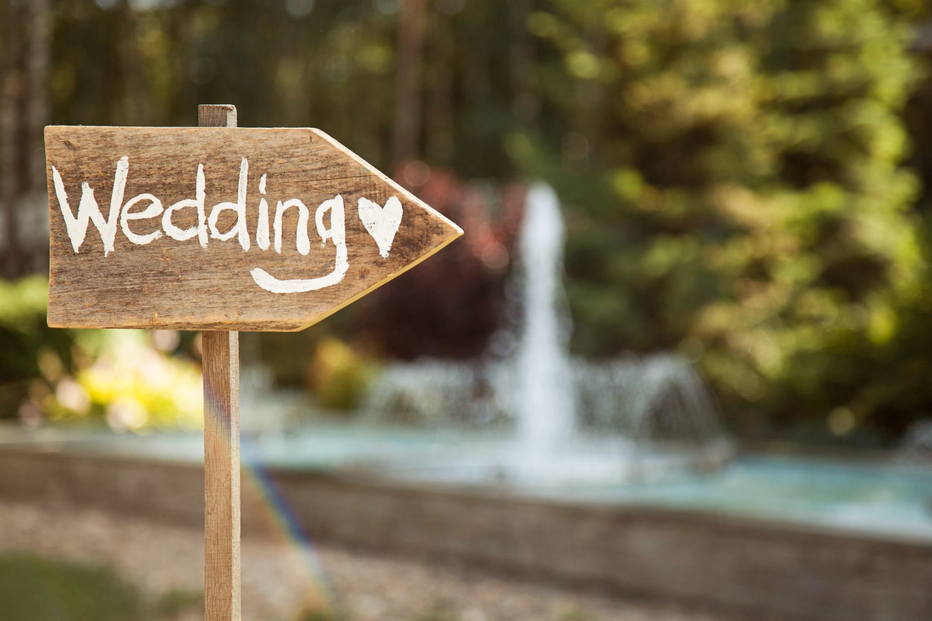 Pancarte en bois « Wedding » devant une fontaine